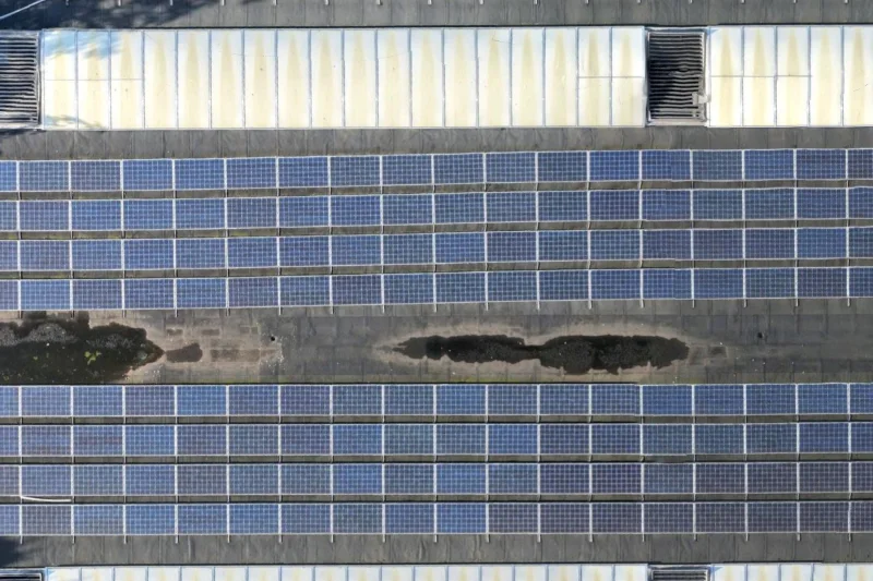 Detail van de dakbedekking tussen twee rijen zonnepanelen met donkere zones op het dakvlak