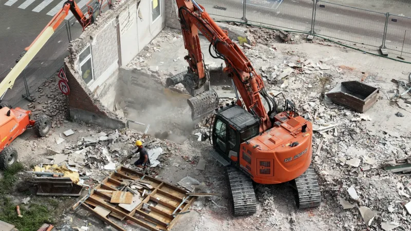 De sloopwerf op 17 juni: een graafmachine met sorteergrijper breekt de laatste muurdelen van de woning af