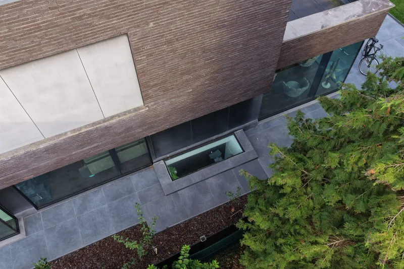Detail van de gevel in donkere baksteen met een lichte gevelplaat en een raam
