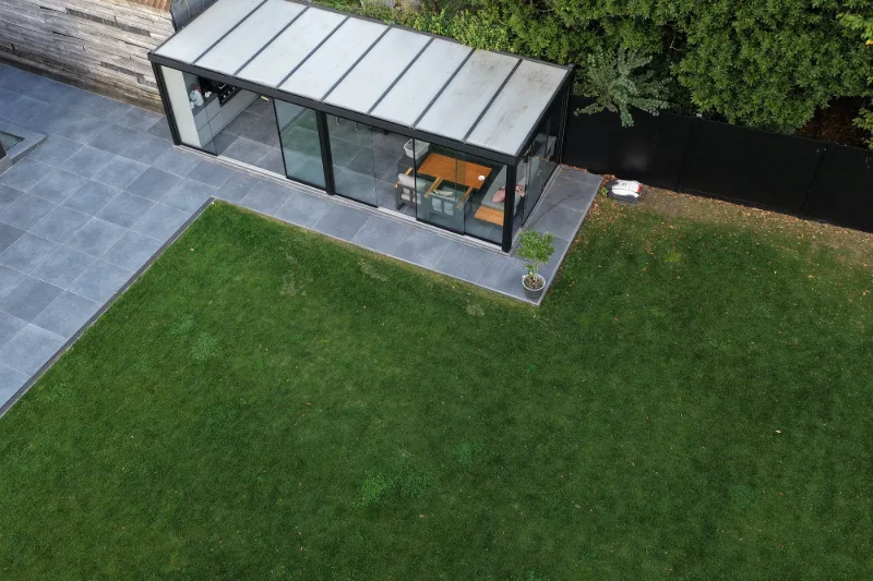 Glazen overkapping aan de tuinzijde naast het terras en het gazon